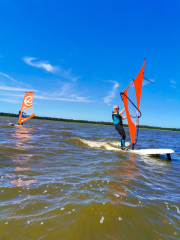 Windsurfer na fali podczas słonecznego dnia – niebieskie niebo i dynamiczna jazda.
