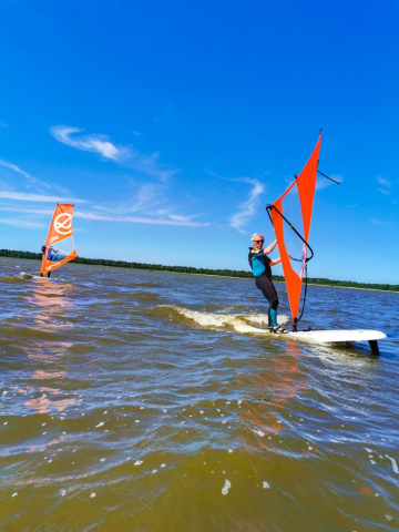 Windsurfer na fali podczas słonecznego dnia – niebieskie niebo i dynamiczna jazda.