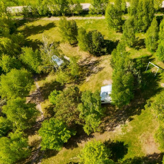 Ujęcie kempingu z lotu ptaka – ścieżki i rozproszone stanowiska wśród drzew.